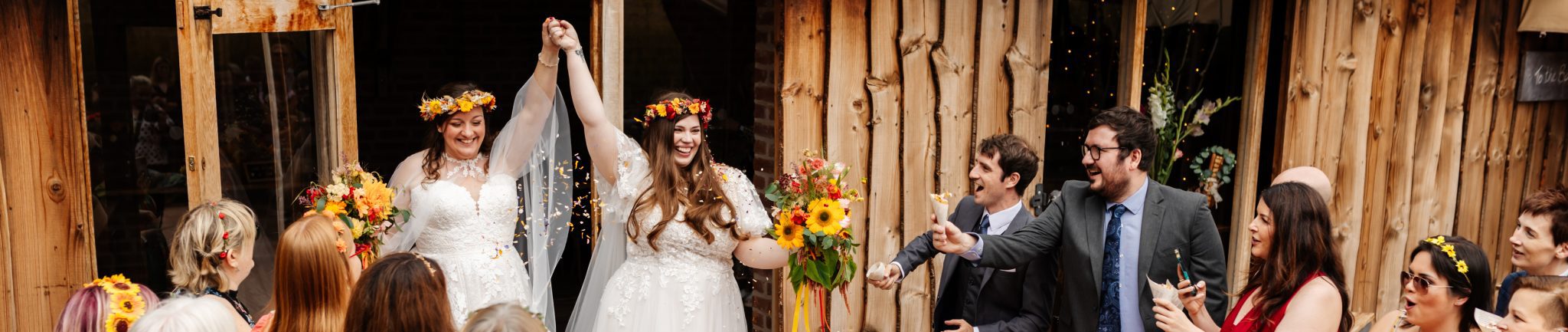 2 brides walking through a confetti tunnel at their wedding at bridal barns in claverly