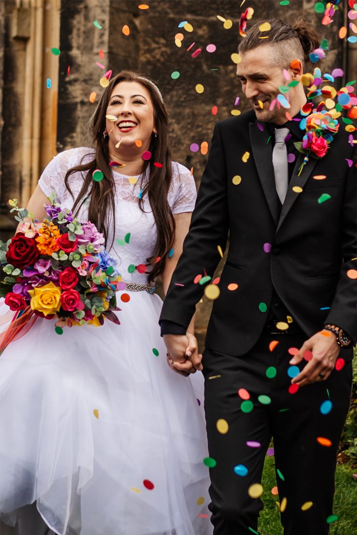 couple grinning covered in rainbow confetti
