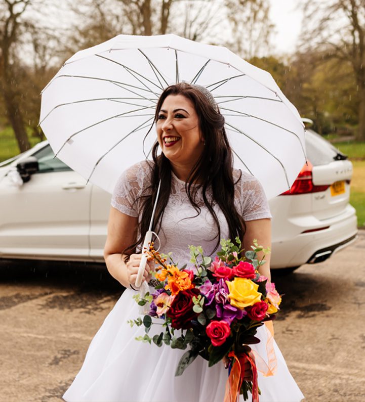 Bride. smiling and holding an umbrella with colourful bouquet