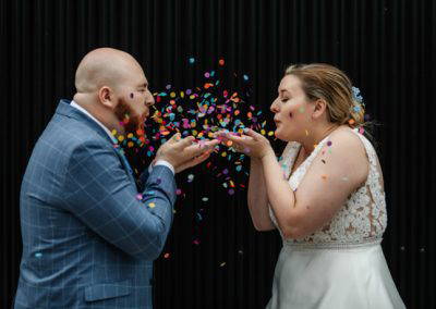 Bride and groom blowing confetti at each other at Shack Revolution