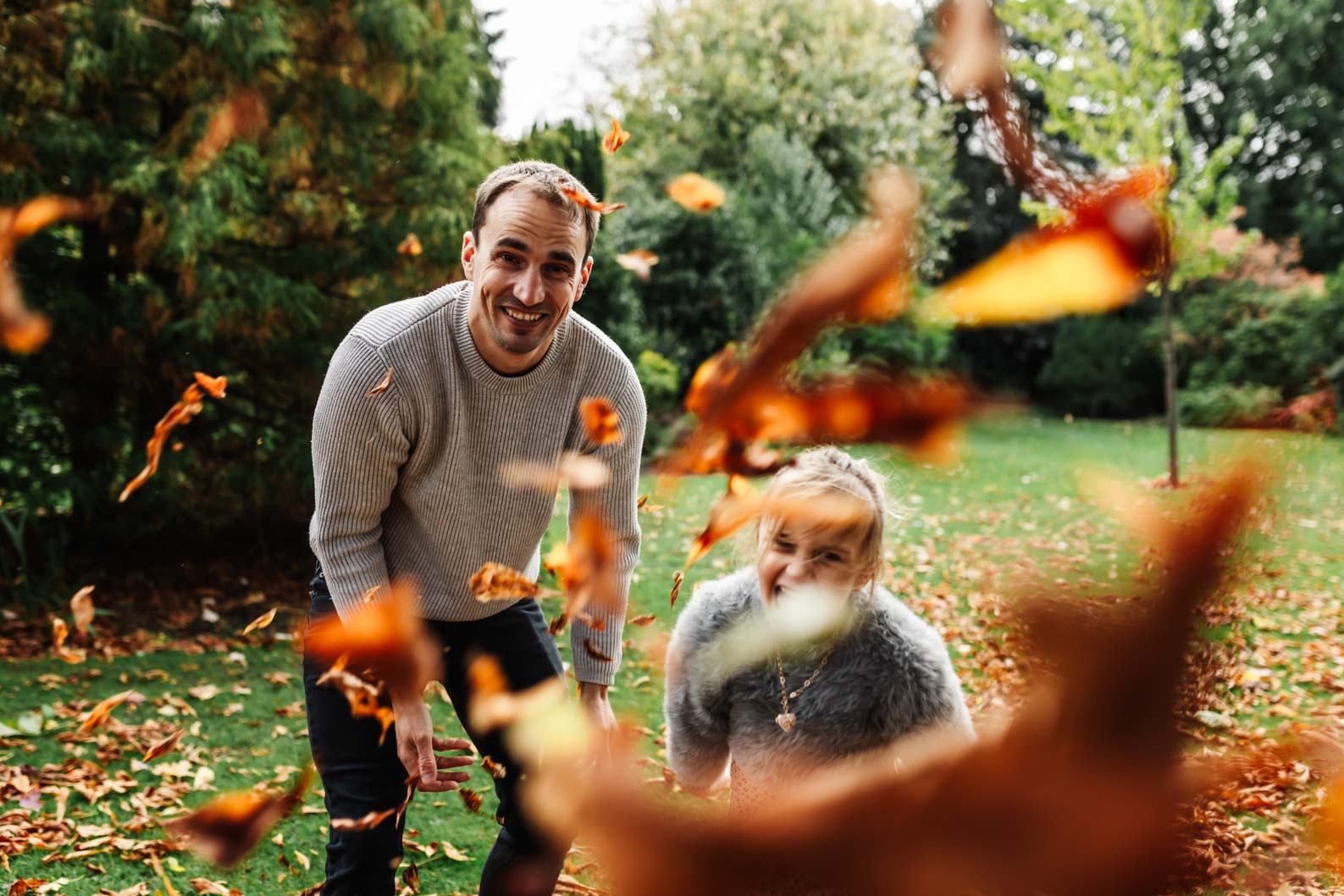Dad and daughter throwing autumn leaves during a family photoshoot in Birmingham