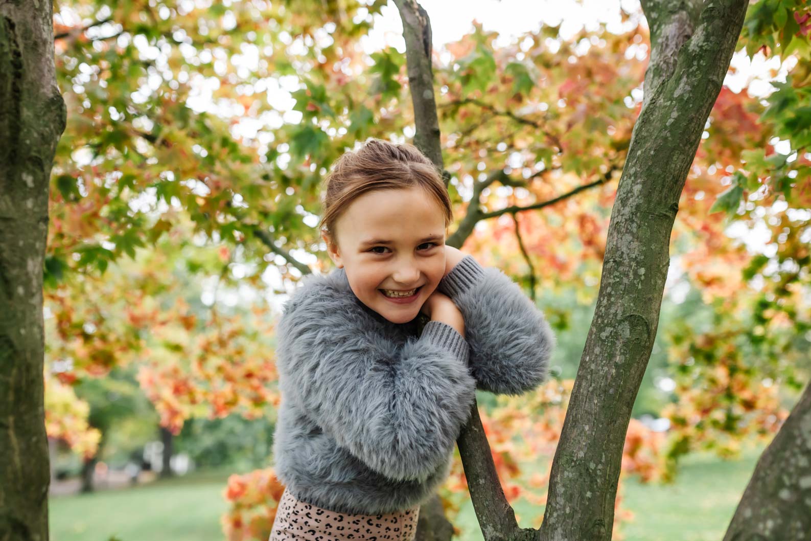 Little girl smiling in a tree during a family photoshoot in Birmingham