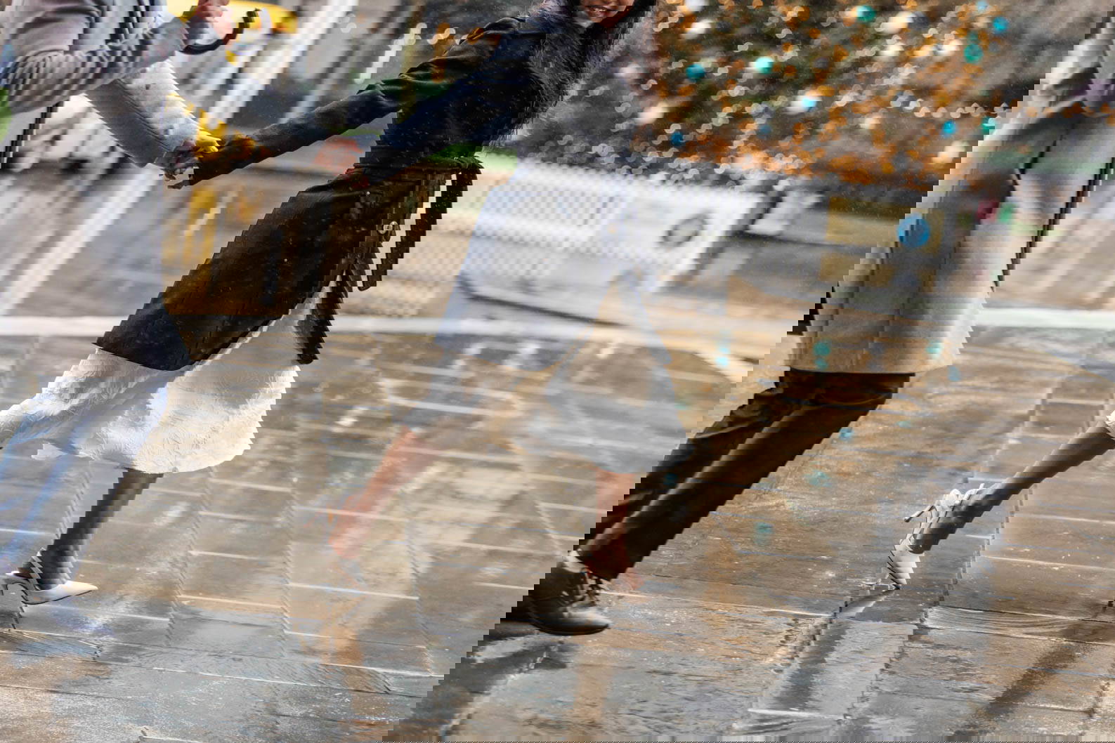 Engaged couple running through the rain in Brindleyplace with city buildings in the background.