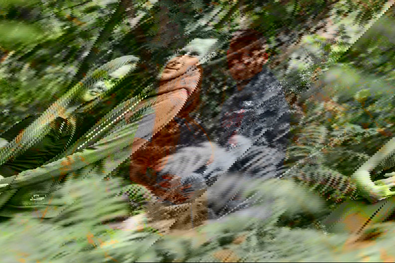 Engaged couple smiling together under trees at Lickey Hills