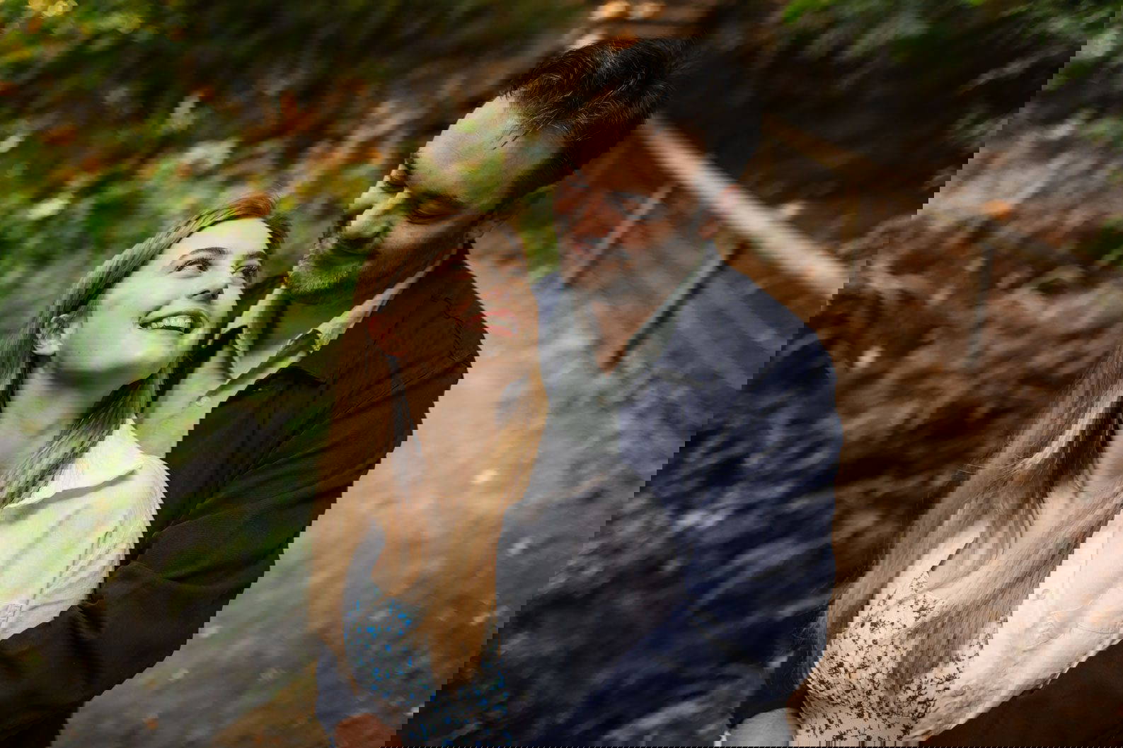 Engaged couple laughing together under trees at Leasowes Park West Midlands.