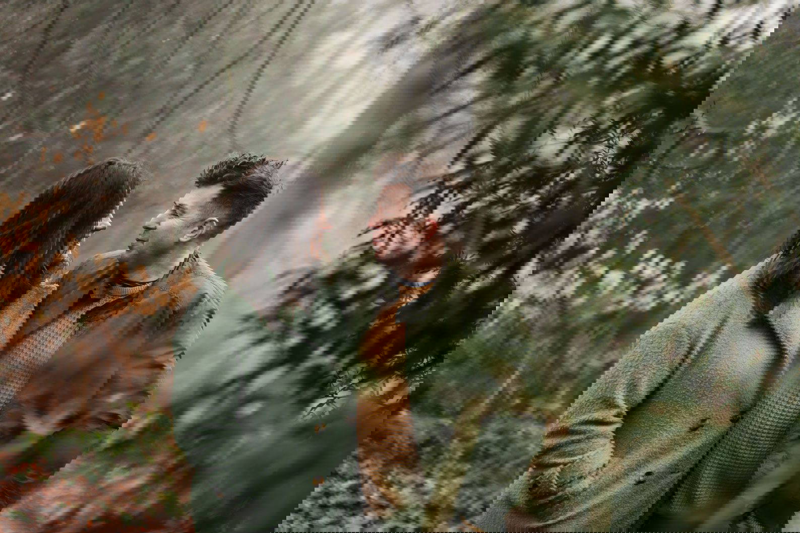 Engaged couple cuddling in woodland at Lickey Hills during a natural pre-wedding shoot.