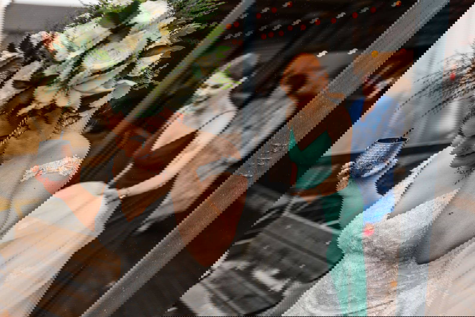 Bride sheltering under her bouquet while a bridesmaid laughs during a rainy wedding in Warwickshire