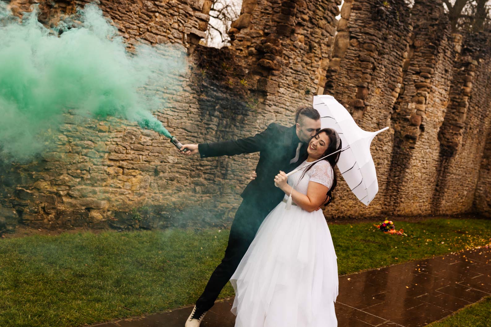 Bride and groom with smoke bomb and umbrella outside Dudley Register Office on a rainy wedding day