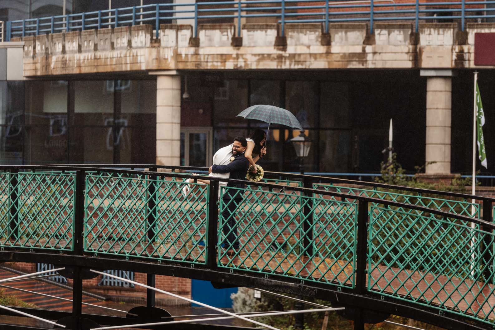 Newlyweds having fun in the rain with an umbrella in Birmingham after their ceremony at Birmingham Register Office