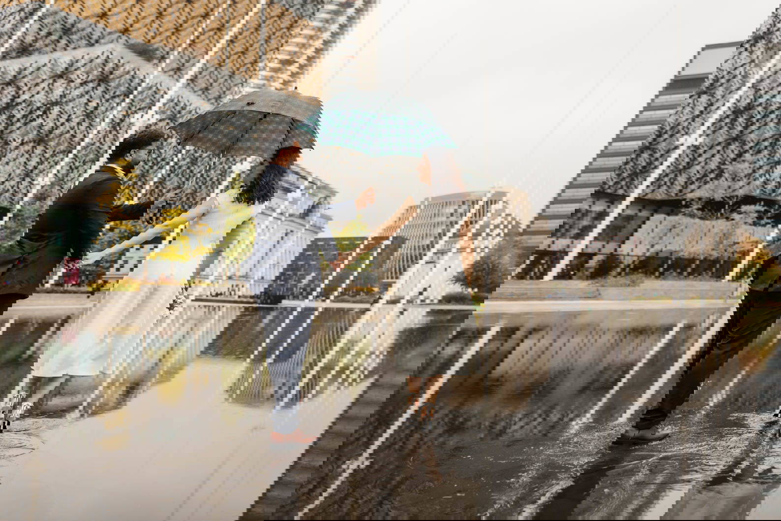 Newly married couple walking in the rain under an umbrella in Birmingham