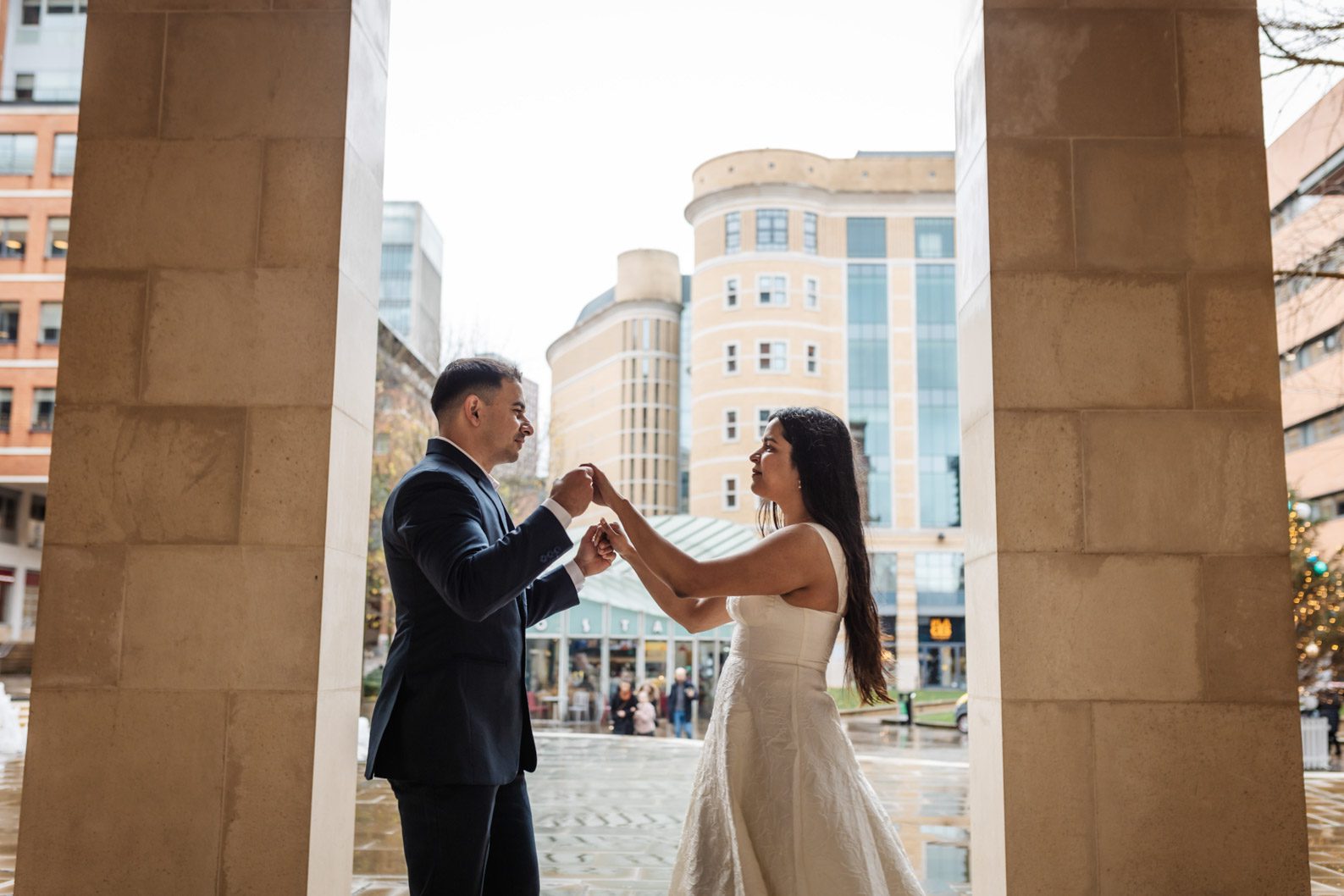 Bride and groom smiling at each other while sheltering under a covered archway during a rainy wedding in the West Midlands